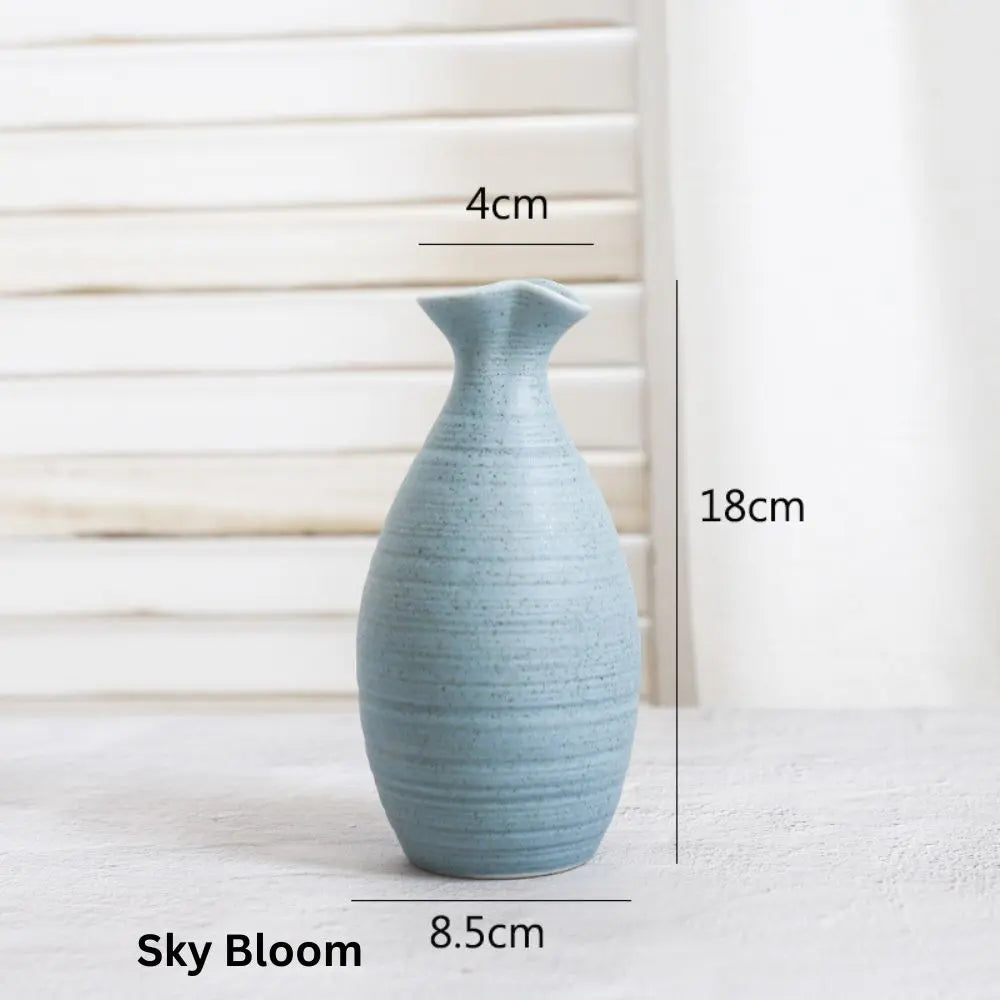 Light blue ceramic vase with a slender body, measuring 18 cm tall and 8.5 cm wide, against a soft, neutral background.