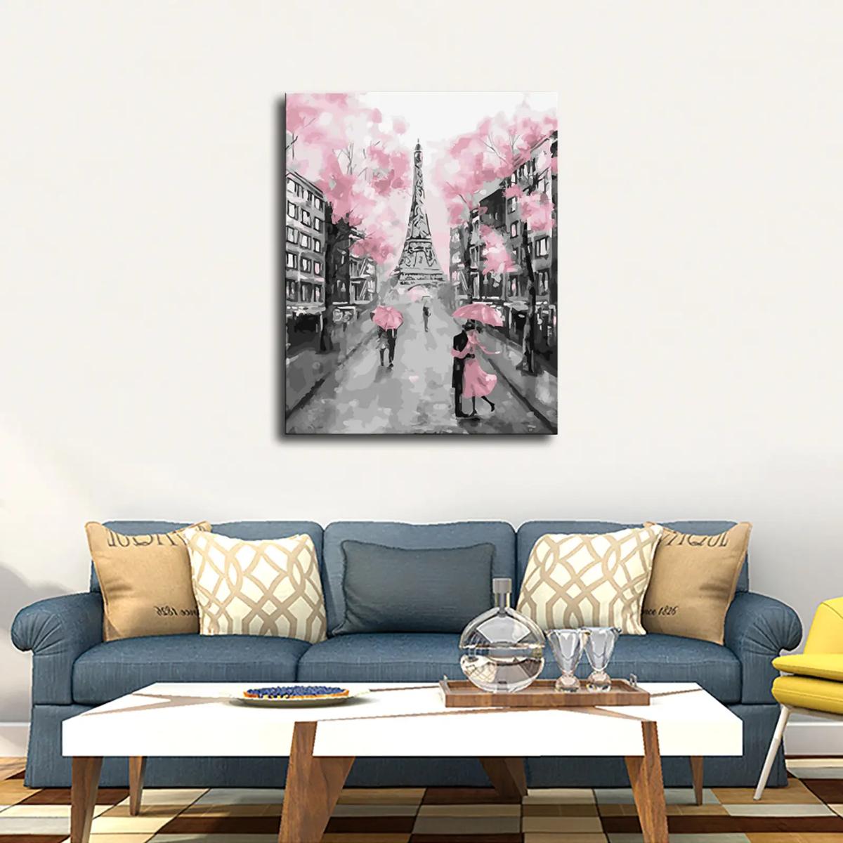 A romantic black-and-white painting of a couple under pink umbrellas in front of the Eiffel Tower, hanging above a stylish couch.