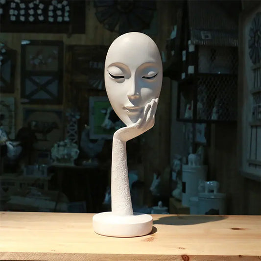 A modern, white sculpture on a wooden table, featuring a curved design with a textured surface, set in a rustic display space.