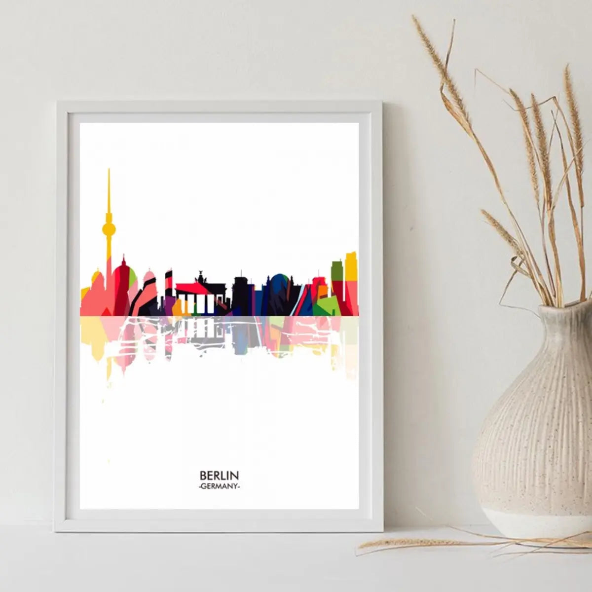 Colorful illustrated skyline of Berlin, featuring iconic landmarks and the text "BERLIN - GERMANY", framed and displayed beside a vase.
