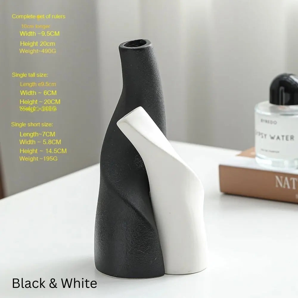 A stylish black and white ceramic vase with curved designs, accompanied by a fragrance bottle and a magazine on a table.