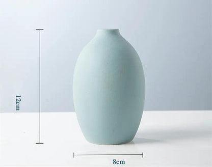 A minimalist light blue ceramic vase, 12cm tall and 8cm wide, displayed against a soft backdrop, showcasing its elegant shape.