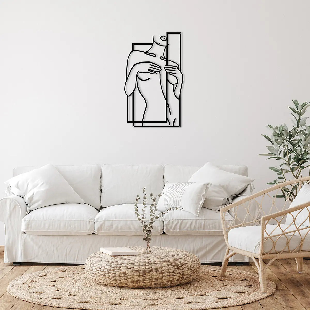 A minimalist wall art piece of a woman's torso framed in black lines, hanging above a cozy white sofa in a stylish living room.