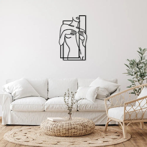 A minimalist wall art piece of a woman's torso framed in black lines, hanging above a cozy white sofa in a stylish living room.